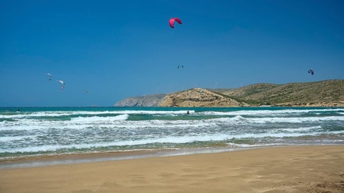 Several kitesurfers on the waves, with a beach and mountains in the background, surfers paradise,