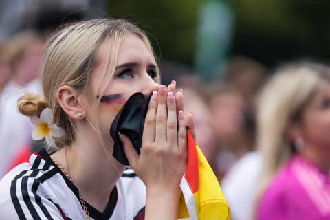 A woman watches the football match in the fan zone at the Brandenburg Tor during the quarter-final