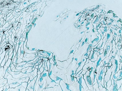Aerial view of frozen lake Prestesteinsvatnet, melting snow creates small blue pools on the frozen