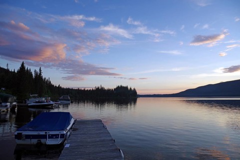 A calm lake at sunset, a jetty with boats and idyllic nature in the background, St. George, British