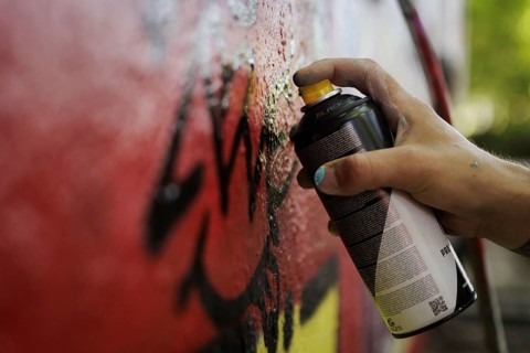 A man sprays graffiti on a wall with a spray can. Berlin, 14.08.2024