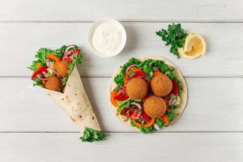 Tortillas, wrapped falafel balls, with fresh vegetables, vegetarian healthy food, on a wooden white