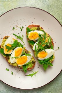 Sandwich with mashed avocado, boiled egg, and arugula, on bread, homemade, breakfast