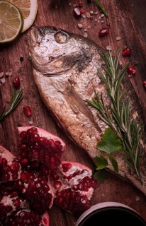 Fried dorado fish, with spices and herbs, on a wooden board, pomegranate sauce, close-up, no people