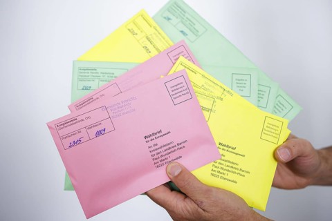 A man holds postal voting documents for the European elections, district council elections and