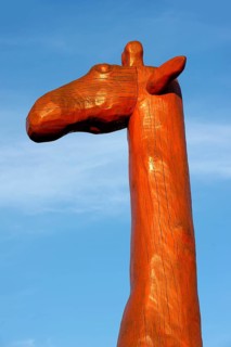 Head and neck of a giraffe made of red painted tree trunks, wooden sculpture by Günter Schumann,