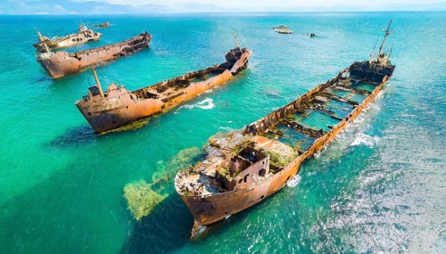 Abandoned, rusty shipwrecks in clear blue water off a coast under a blue sky, symbol photo, AI