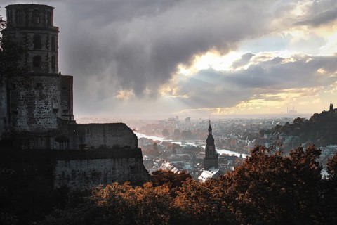Romantic view of the city of Heidelberg with river and castle under a dramatic sky and falling