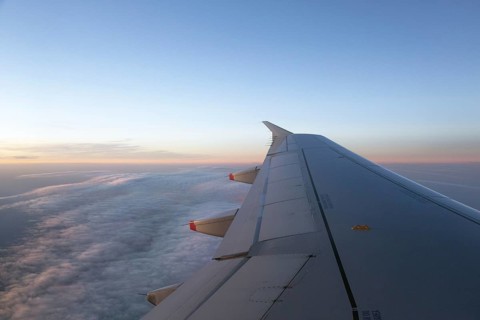 View out of the aircraft window onto the wing and the clouds during sunrise