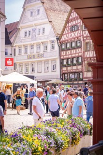 Market scene in front of a half-timbered house and a pharmacy, animated by people and decorated