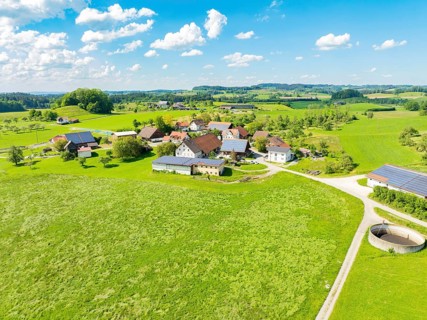 Aerial view of an extensive meadow landscape with a village and farms, glass fibre installation,