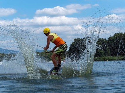 Sporty man with jump with wakeboard, water sports, water skiing and wake park