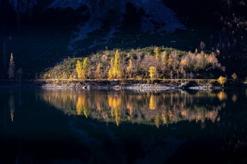 The Vordere Gosausee in autumn. Part of the path around the lake lies in the sun, the scene is