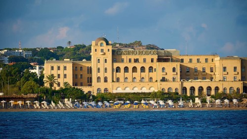 Casino building on the beach with parasols and clear sea, harbour area, Rhodes Town, Rhodes,