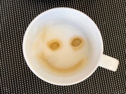 Coffee drink cappuccino with milk foam decorated to smile like emoji smiley, international