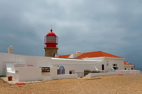 A white building with a red lighthouse under a cloudy sky, Cape St Vincent, Cape St Vincent, Cabo