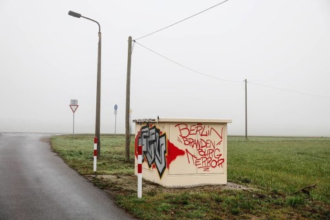 An electricity box sprayed with the phrase Berlin Brandenburg Terror stands at a crossroads on a