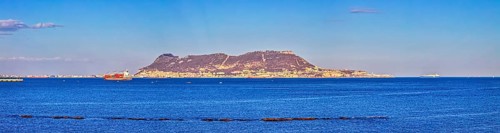 Clear sea with an island in the background and passing ships under a blue sky, Algeciras