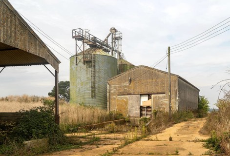 Grain storage silos and asbestos barn in farmyard, Alderton, Suffolk, England, UK