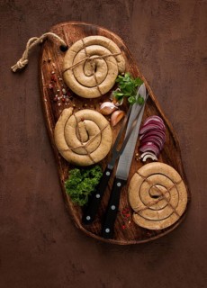Raw spiral sausages, on a wooden board, top view, with spices, no people