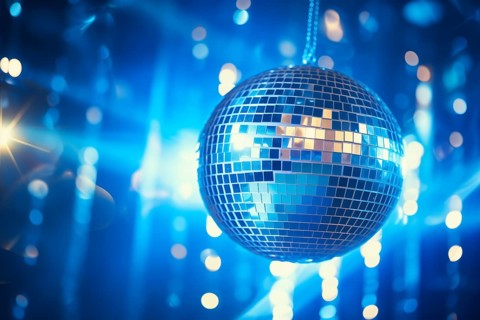 A disco ball is suspended from the ceiling at party, reflecting the lights and creating a festive
