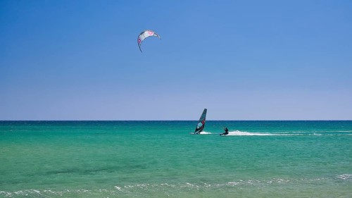 A person windsurfing in a clear blue sea under a sunny sky, surfers paradise, kitesurfer,