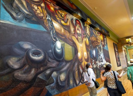 People viewing artwork 'Nueva Democracia' 1944 mural by David Alfaro Siqueiros, Palacio de Bellas