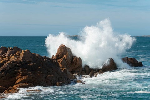 High waves crash against a rocky coastline under a clear sky, Ploumanac'h, Ploumanach,