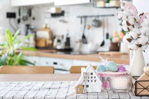 Key to house of cozy home with Easter decor with rabbit and eggs on table of kitchen. Building,
