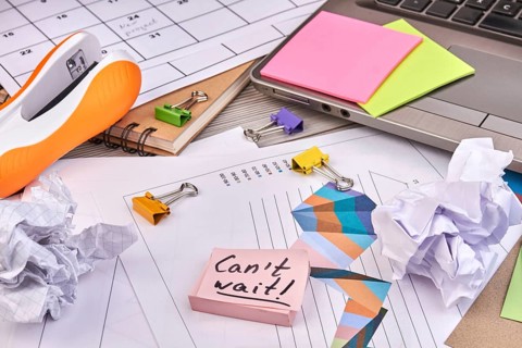 Close-up sticky notes with cant wait handwriting and office stuff. Work papers with charts and