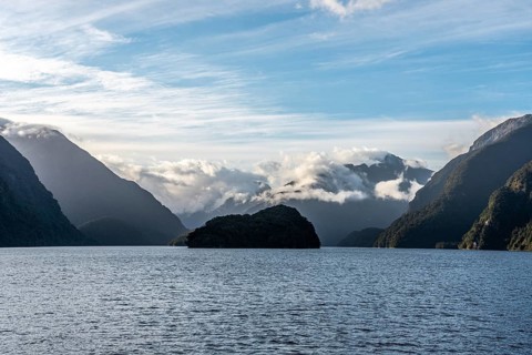 Sun rising over Doubtful Sound, Clouds hanging low on the mountains, South Island of New Zealand