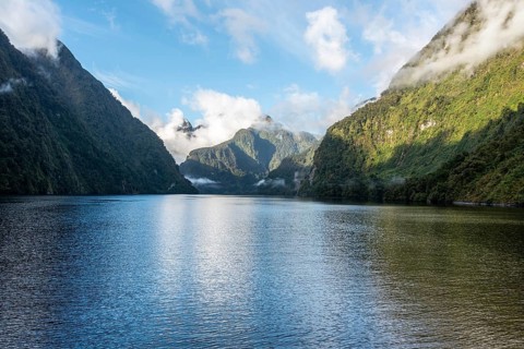 A new morning dawning at Doutful Sound, clouds hanging low in the mountains, South Island of New