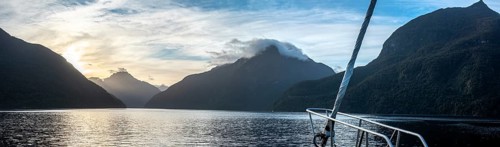 Sun rising over Doubtful Sound, Clouds hanging low on the mountains, South Island of New Zealand