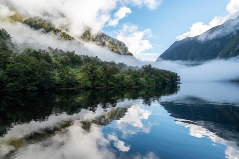 A new morning dawning at Doutful Sound, clouds hanging low in the mountains, South Island of New