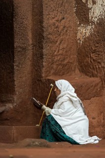 Ethiopian Orthodox woman prays at the entrance to the rock-hewn church of Biete Gabriel-Rufael,