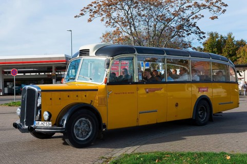 Yellow vintage bus in retro style drives past a road with autumn trees, vintage car, Saurer,