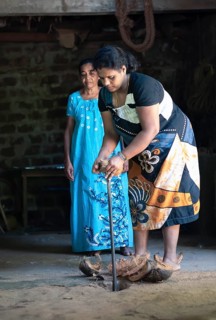 Sri Lankan woman opening coconuts using an ancient method, Matale, Central Province, Sri Lanka,