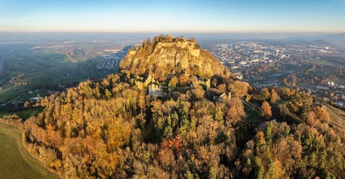 Aerial view of the Hohentwiel volcanic cone with the castle ruins illuminated by the evening sun,