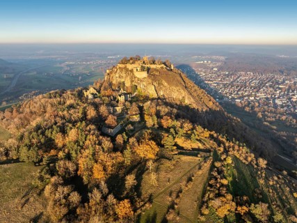 Aerial view of the Hohentwiel volcanic cone with the castle ruins illuminated by the evening sun,