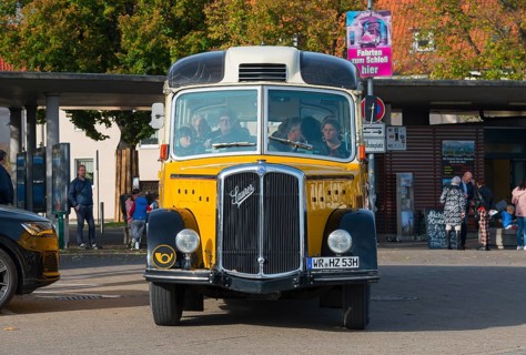 Front view of a yellow vintage bus with people in an urban environment, vintage car, Saurer,