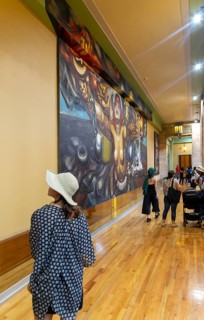 People viewing artwork 'Nueva Democracia' 1944 mural by David Alfaro Siqueiros inside Palacio de