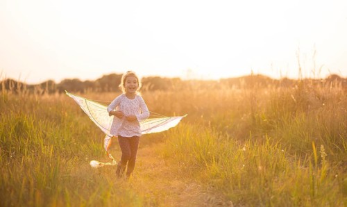 A girl runs into a field with a kite, learns to launch it. Outdoor entertainment in summer, nature