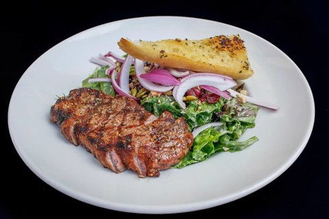 NY Strip steak with brown butter, accompanied by sautéed vegetables and a peppercorn demi-glace