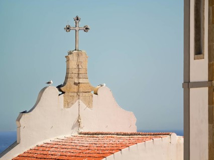 Mother Church cross and rooftop with sky and ocean in the background, Albufeira, Algarve, Portugal,