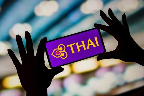 In this photo illustration, the Thai Airways International logo is displayed on a smartphone screen