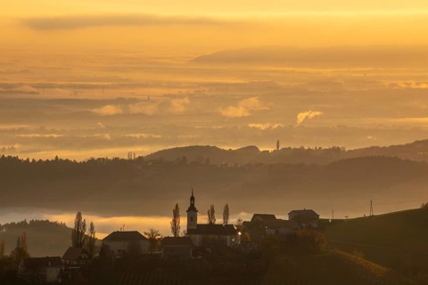 Autumn atmosphere in the golden morning light, fog drifts over the hilly landscape, silhouette of
