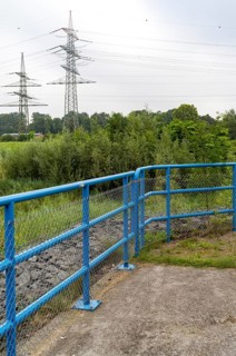Blue metal railing in front of high voltage pylons