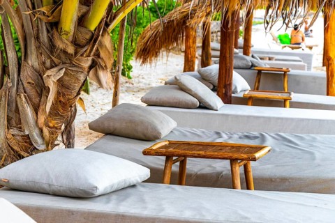 Palapa thatched roofs palm trees parasols umbrellas and sun loungers at the beach resort hotel on