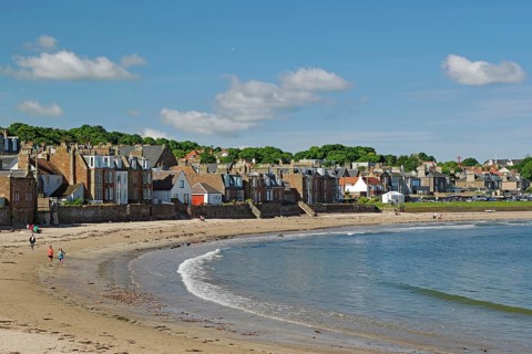 Houses along a beach with walkers by the sea under a blue sky on a sunny day, North Berwick,