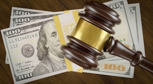 Overhead of gavel resting on a table and stack of thousands of dollars